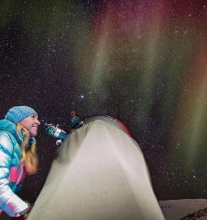 一位女士站在星空下的帐篷旁