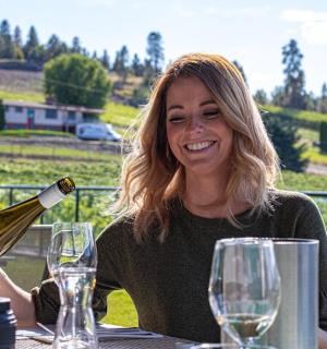 一位女士坐在桌边倒了一瓶酒