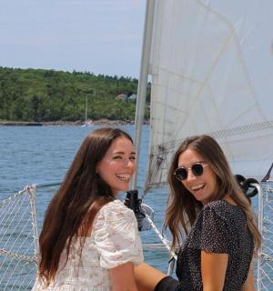two women standing on a sail boat in the water