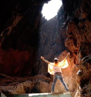 a man standing in a cave with his arms up