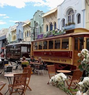 a trolley car is parked next to tables and chairs