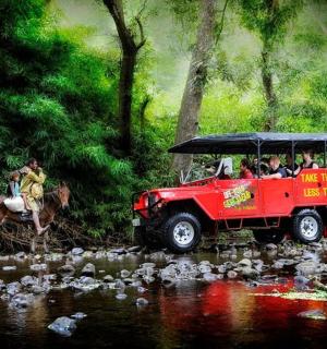 一辆红色吉普车,车里坐着人,停在河边