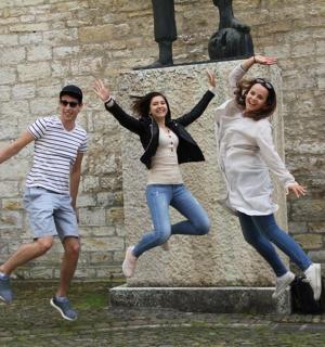 Un grupo de tres personas saltando frente a una estatua