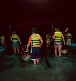 一群人站在水中，手里拿着皮划艇