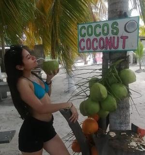 a woman is standing next to a coconut sign