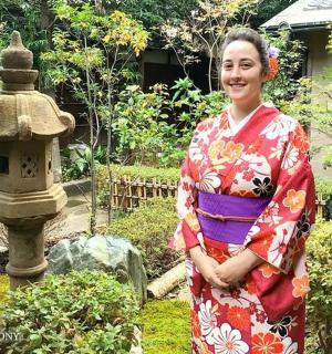 a woman in a kimono standing in front of a garden