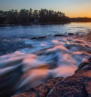 ein Gewässer mit der untergehenden Sonne im Hintergrund