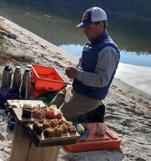 一名男子站在海滩上,手里拿着一盘食物