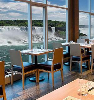 a restaurant with tables and chairs and a view of a waterfall