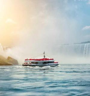 a boat in the water in front of a waterfall