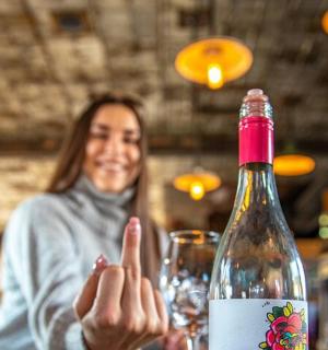 一位女士坐在桌边,手里拿着一瓶酒