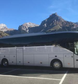 a white bus parked in a parking lot with mountains