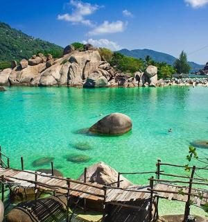 a pool of blue water with rocks and people in it