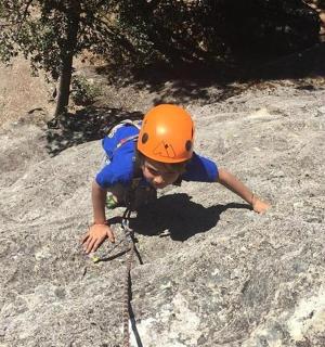 Mladý chlapec v oranžové helmě si hraje v písku