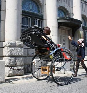 一名男子站在建筑物前的一辆自行车旁