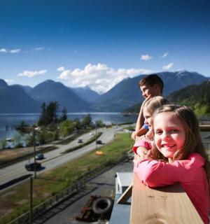 Ein Mann und zwei Kinder stehen auf einem Balkon mit Aussicht