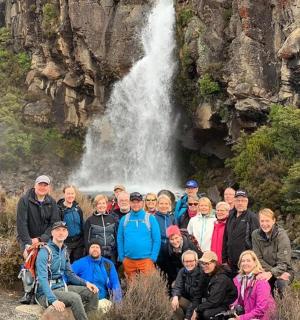 a group of people posing in front of a waterfall