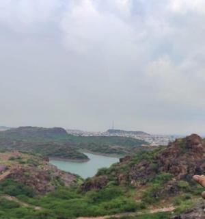 a person pointing at a lake from a mountain