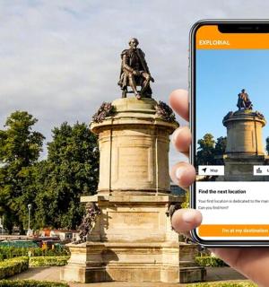 a person holding up a cell phone in front of a statue