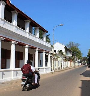 a man riding a motorcycle down a street with a dog