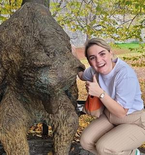 a woman kneeling next to a statue of a bear