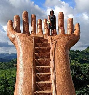 uma mulher em pé em cima de uma mão gigante