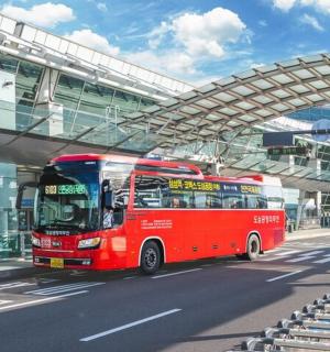 a red bus driving down a street under an overpass