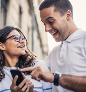 ein Mann und eine Frau schauen auf ein Mobiltelefon
