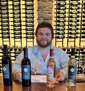 一位男士坐在桌边，桌上放着四瓶酒