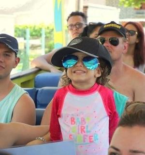 mladá dívka se slunečními brýlemi a kloboukem a skupina lidí