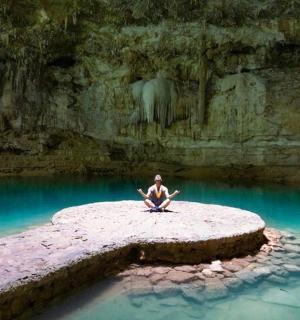 a person sitting on a rock in the water