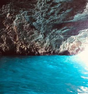 a blue pool of water next to a cliff