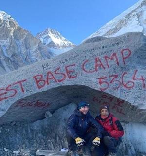 两个人坐在山上的一块标志牌前