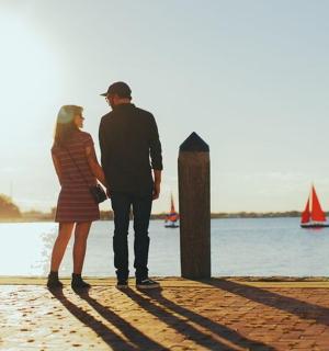 muž a žena stojící na pláži a dívající se na vodu