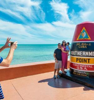 a man taking a picture of a group of people standing next to a boat