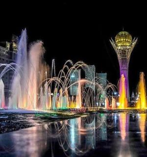 a water fountain in front of a city at night