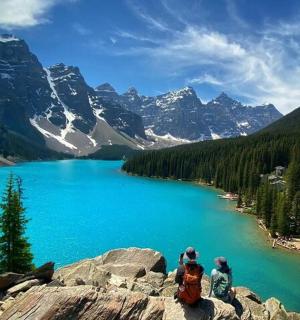 a group of people sitting on a rock near a lake
