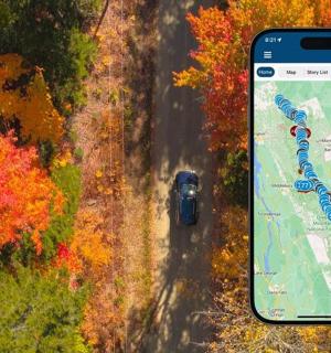 a car driving down a road with a large cell phone