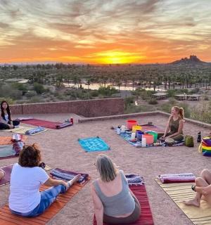 a group of people sitting on the ground watching the sunset