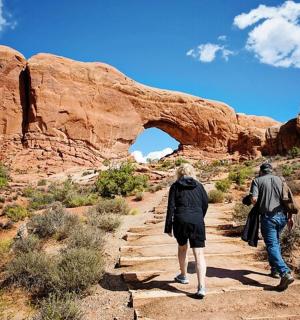 two people walking through an arch in the desert