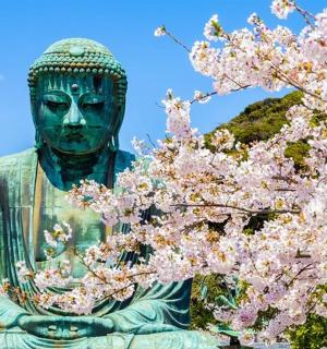 a statue in front of a tree with pink flowers