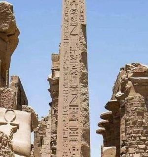 a tall obelisk in a building next to a statue