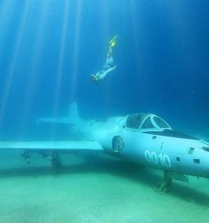 uma pessoa nadando no oceano ao lado de um avião