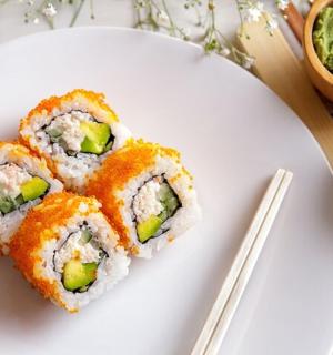 一个白色的盘子，上面放着寿司和筷子