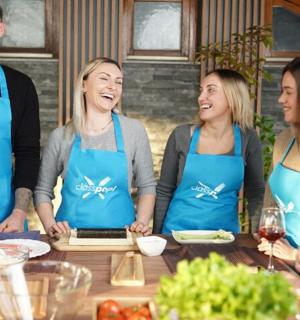 skupina lidí v zástěrách stojících kolem stolu