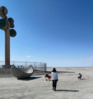 一名女子在船边的海滩上散步