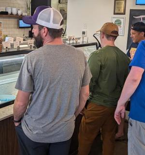 a group of men standing in a kitchen preparing food