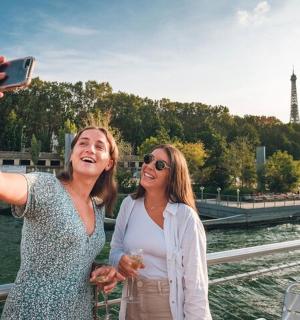 two women taking a picture of the eiffel tower