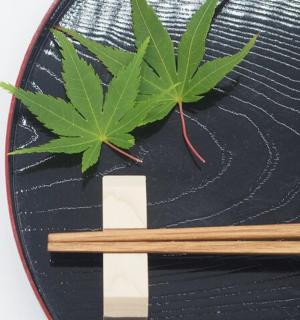 zelený list na černém talíři s hůlkami