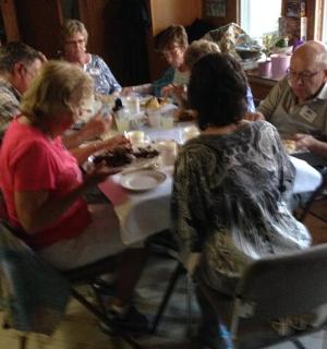 grupa ludzi siedząca przy stole i jedząca